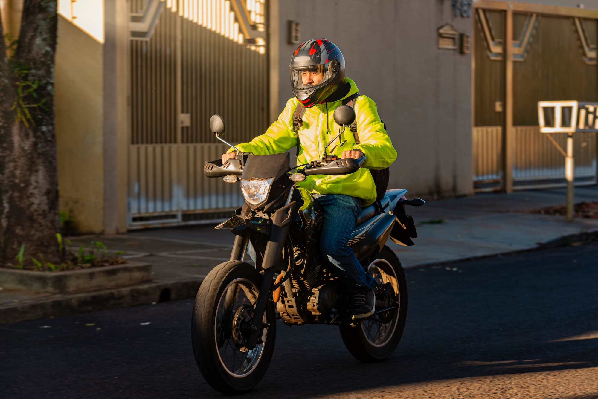 Jeune homme conduisant une moto A1, portant un casque homologué et une veste jaune pour sa sécurité routière